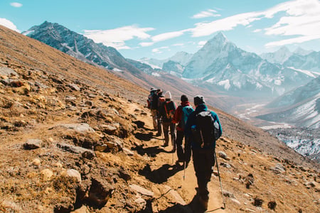 A team hikes a path to the mountains